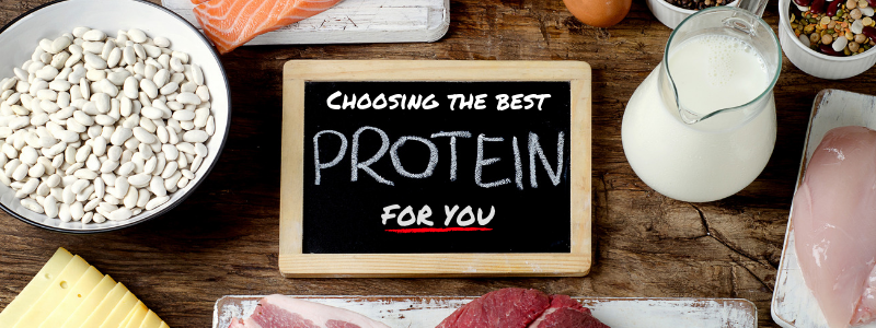 Various source of protein on a table surround a chalk board that reads "Choosing the best protein powder for you"