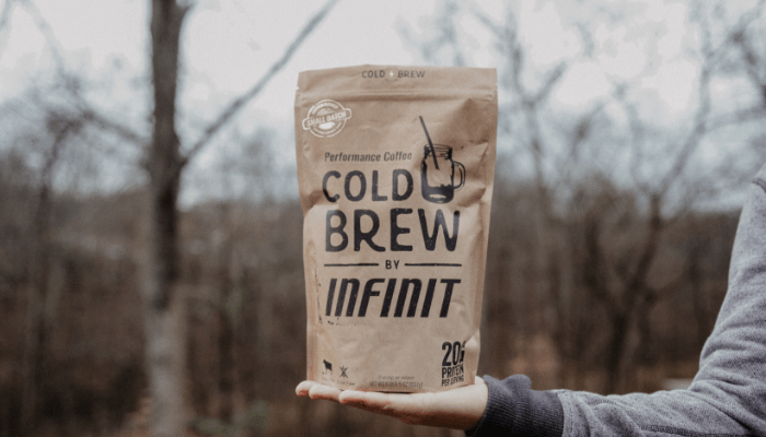 Woman arm holding out an INFINIT Cold brew bag in the woods